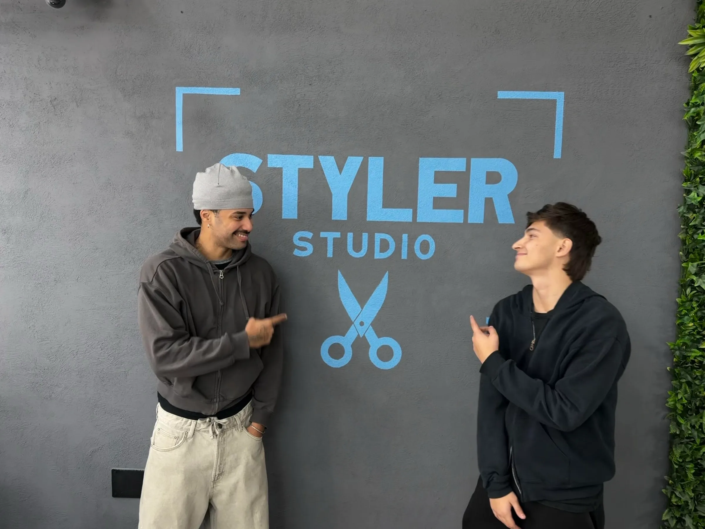 A Styler Studio két alapítója a szalon logós fala előtt
